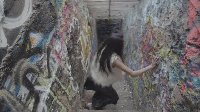 An interpretive dancer in slow motion flips her long dark hair around in circles and then crawls up towards the camera, reaching at the lens