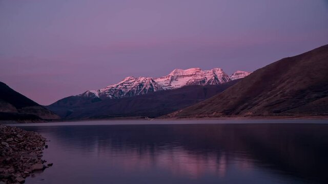 Reflection of snow capped Timpanogos Mountain reflecting in Deer Creek Reservoir during sunrise timelapse in Utah.