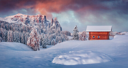 Panoramic morning view of Alpe di Siusi village with wooden chalet. Attractive winter sunrise in Dolomite Alps with Santner and Euringer peaks on background. Stunning landscape of ski resort, Ityaly.