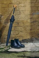 Men's shoes with an umbrella and a walking stick are on the street