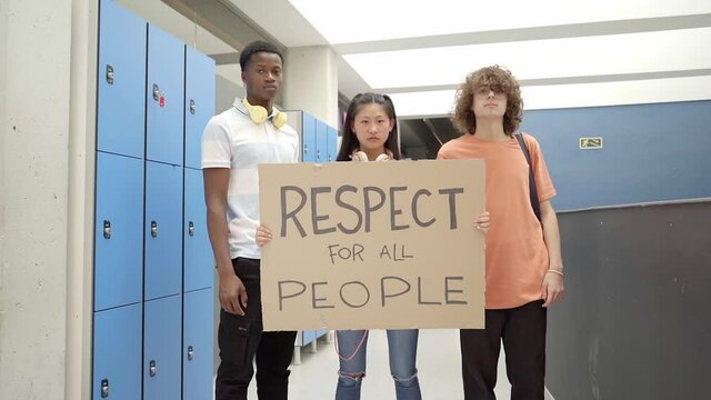 Multi-ethnic group of students carrying a banner on which is written the phrase: Respect for all people. Teenager demonstrating for rights.