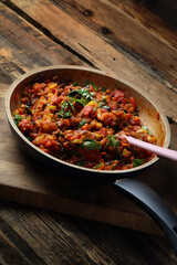 Vegetables stewed in a frying pan: carrots, garlic, tomatoes, eggplant and parsley