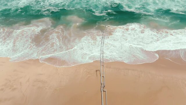aerial drone revealing endless wild sea breaking on sandy coastline.