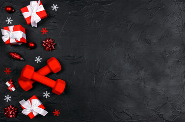 Red dumbbells with winter decorations on black background.
