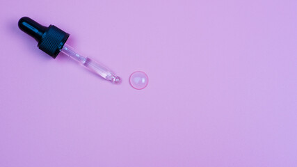 Dropper with cosmetic gel on a pink background.