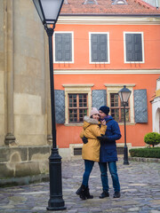 People Embracing by ancient architecture landmark. Tourists Walking Together On Lviv City Street, Family Couple Talking. Young tender couple hugging and kissing outdoors in the Armenian quarter.
