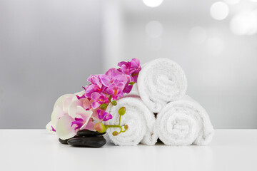 Fototapeta na wymiar Towels with flowers on light table against blurred background