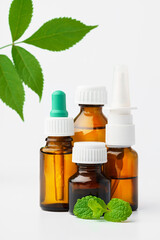 Essential oil in a small bottle with green leaf on white background