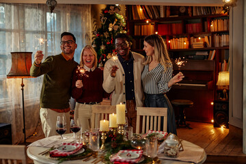 Friends celebrating Christmas with fire sparkles at party