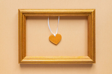 Valentine's day or Wedding romantic concept. golden photo frame with wooden heart inside on beige background
