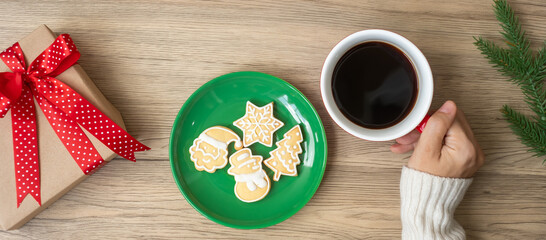 Merry Christmas with woman hand holding coffee cup and homemade cookie on table. Xmas eve, party, holiday and happy New Year concept