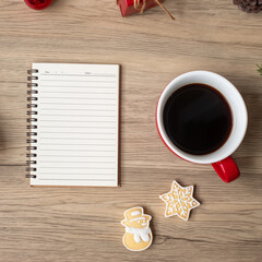 Blank notebook, black coffee cup, Christmas cookies and pen on wood table, Top view and copy space. Xmas, Happy New Year, Goals, Resolution, To do list, Strategy and Plan concept