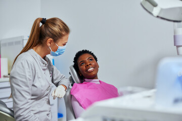 Female patient sitting in the dental chair and talking to her dentist
