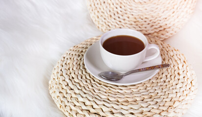 Selective focus of white ceramic cup of hot black coffee on white fur background -cozy mood