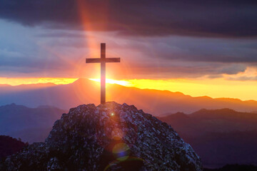 Silhouettes of crucifix symbol on top mountain with a bright sunbeam on the colorful sky...