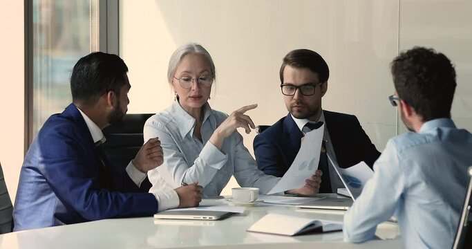 Middle-aged and millennial businesspeople reviewing statistical data, learning infographic information on graph and diagrams, analyzing and forecasting, make financial research at meeting in boardroom