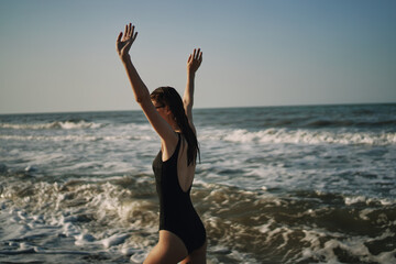 Fototapeta na wymiar woman in black swimsuit walking on the beach ocean summer