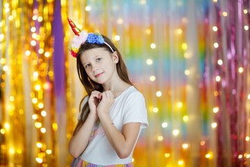 Funny cute girl with long hair in dress and a unicorn headband with tattoos on her face on a...