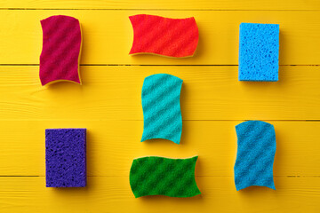 Cleaning sponges on yellow wooden background flat lay