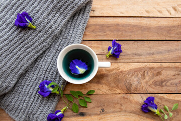 Obraz na płótnie Canvas herbal drinks hot butterfly pea water for health care with knitting wool scarf arrangement flat lay style on background wooden