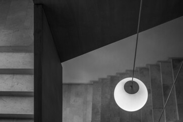 Round pendant lamp with a handrail at the top and stairs at the bottom. Horizontal view. Black and white.