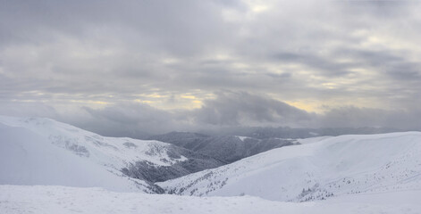 Fototapeta na wymiar Panoramic view to snow-covered mountain slopes at sunset. Winter landscape. Carpathian Mountains.