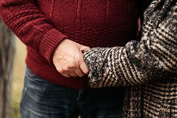Senior man in love holding and caressing tender hands of his beautiful woman, husband warming cold...