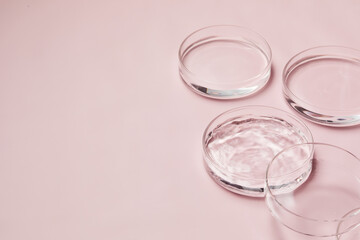 Petri dishes with water and ripple in light pink background 