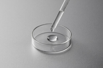 Petri dish and dropper with liquid in silver background