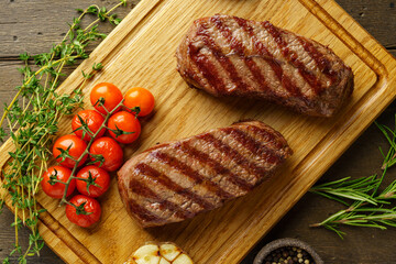 Horizontal of ketogenic juicy and tender two top blade beefsteaks on wooden board with seasonings
