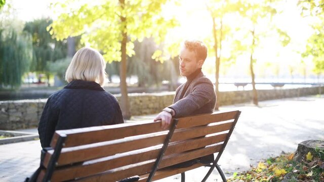 Grandmother with young guy in formal clothes have conversation in an autumn park