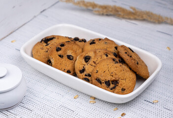 Cookies with chocolate drops in a white plate on a white background