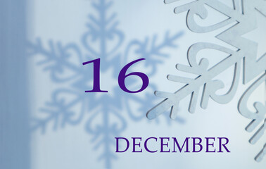 Calendar for December 16: name of the month in English, number 16 on a blue background of snowflakes and their shadows.