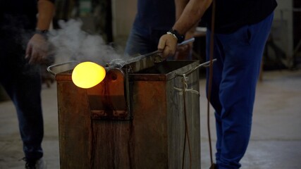 Murano, Venice,Italy November 2021 : Making famous Venetian glass in Murano, glass making - actual process inside the factory in Venice - 
cooling the glowing glass ball