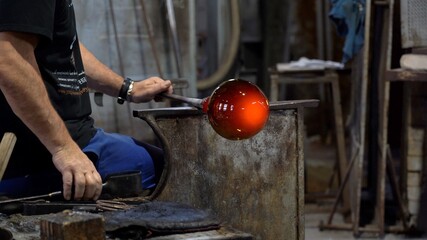 Murano, Venice,Italy November 2021 : Making famous Venetian glass in Murano, glass making - actual process inside the factory in Venice - 
cooling the glowing glass ball - obrazy, fototapety, plakaty