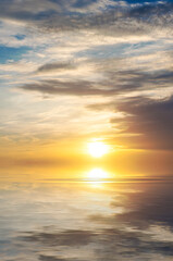Fototapeta na wymiar Cloudy sunrise in the sky with bright sun in the clouds over the sea.
