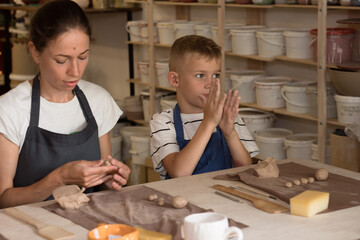 Mother and teenager son spend time together and sculpting from clay in pottery school