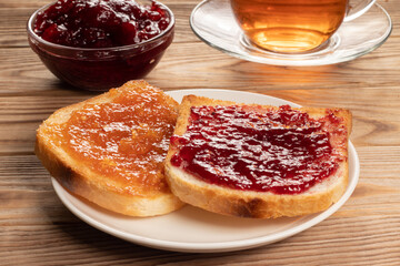 Close-up view of toasts with red and orange jam on white plate.