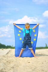 Little boy with the flag of the European Union against the blue sky.