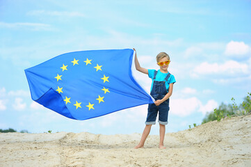 Little boy with the flag of the European Union against the blue sky.