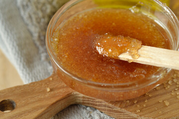 Close-up of homemade lip scrub made out of brown sugar, honey and olive oil in glass bowl on wooden...
