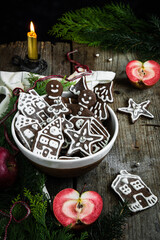 Bowl with homemade gingerbread cookies in men, house, tries and star shapes on old wooden table.