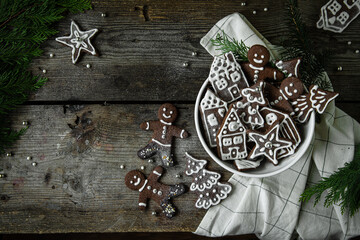 Bowl with homemade gingerbread cookies in men, house, tries and star shapes on old wooden table.