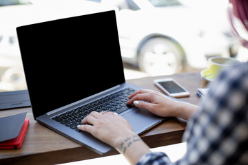 Woman typing on notebook with blank screen with copy space for your text or advertising content, sitting at wooden table