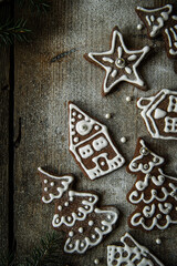 Homemade Christmas gingerbread village with Christmas trees, houses and men sprinkled with icing sugar on rustic wooden table.