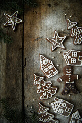 Homemade Christmas gingerbread village with Christmas trees, houses and men sprinkled with icing sugar on rustic wooden table.