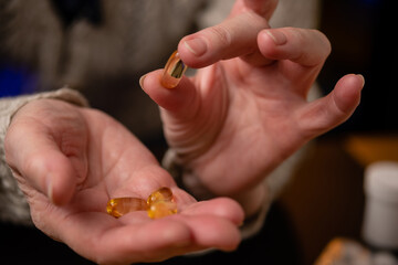 Elderly woman holds fish oil capsules in her hands. Omega 3 and old age.