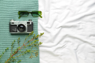 Photo camera and stylish glasses on fabric background