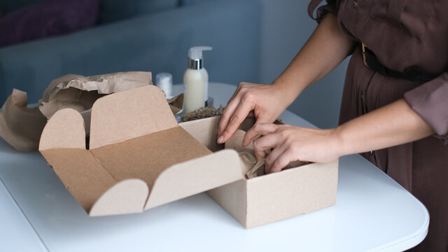 Woman Opening Parcel Indoors. Woman Opening And Unpacking Cardboard Box Parcel In Living Room At Home. Good Delivery Service.