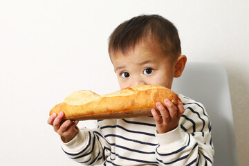 大きなフランスパンを食べているカワイイ男の子。 - obrazy, fototapety, plakaty